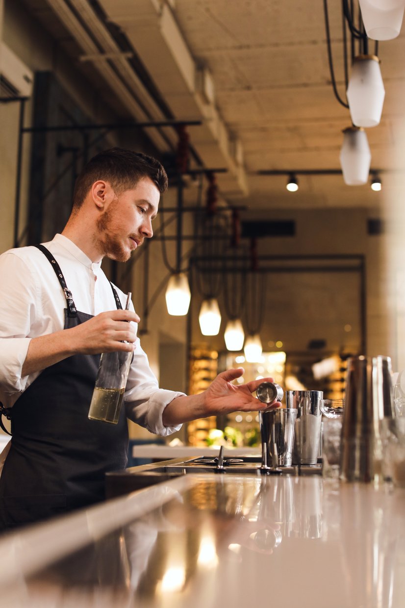 Man in Black Vest Holding Clear Glass Bottle